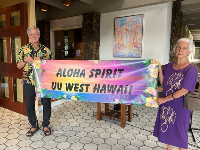 Two people holding a banner that says "Aloha Spirit UU West Hawaii"